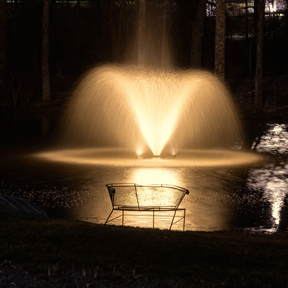 private pond with lighted fountain at night
