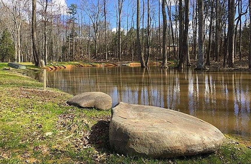 large stone lying beside a private pond